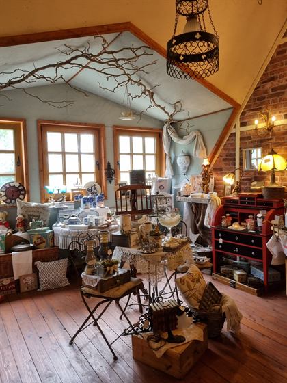 Blick in den Dachboden-Laden mit roter Kommode, Kronleuchtern und Ast-Installation