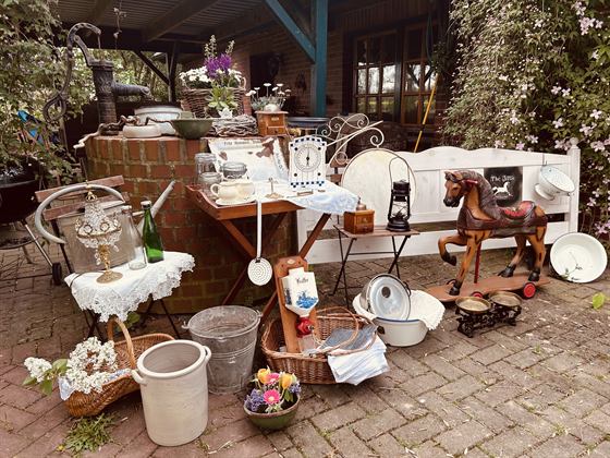 Buntes historisches Schaukelpferd vor dem Hof, umgeben von Körben und Emaille