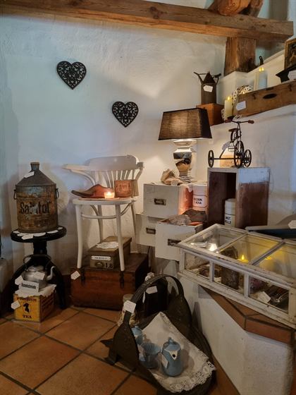 Shabby-Chic-Ecke mit weißem Stuhl, gusseisernen Herzen und Vitrinen-Aufsatz